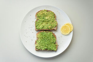 two slices of bread spread with avocado